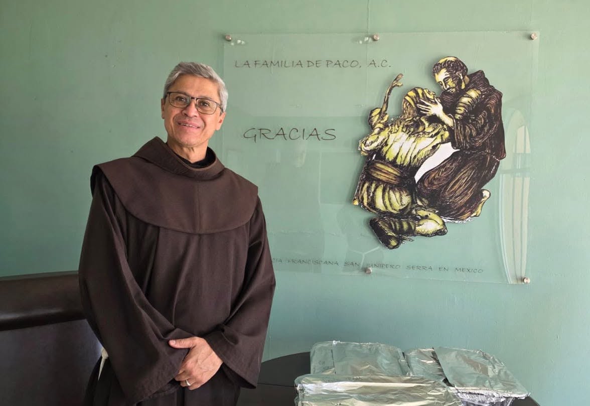 Fraile franciscano junto a una representación de san Francisco de Asís abrazando a un leproso en Casa de Paco, Mexicali.