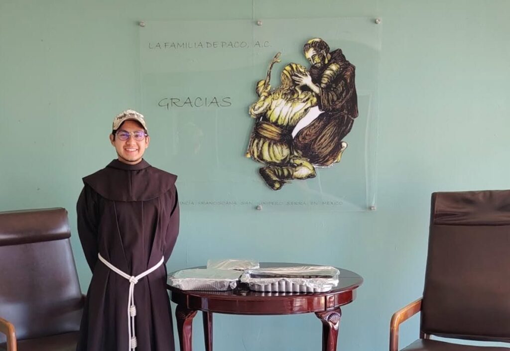 Joven fraile franciscano en las instalaciones de Casa de Paco, frente al emblema de La Familia de Paco A. C.