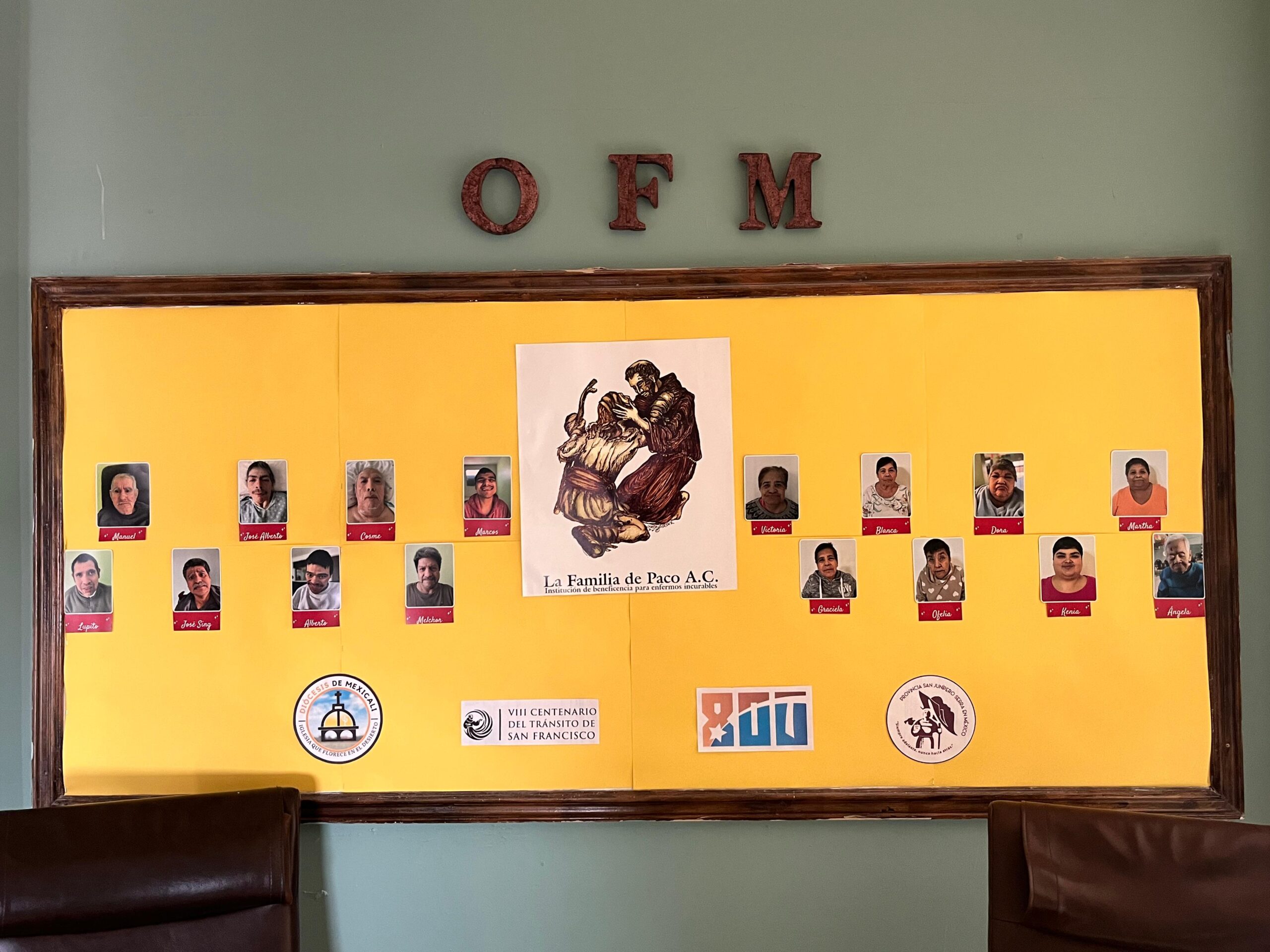 Mural con fotografías de residentes de Casa de Paco, acompañado del emblema de la institución y símbolos franciscanos.